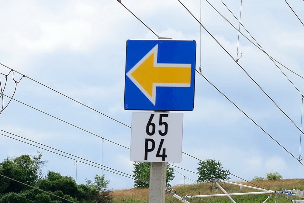 Tablica ETCS Stop Marker przy torze — niebieska z żółtą strzałką